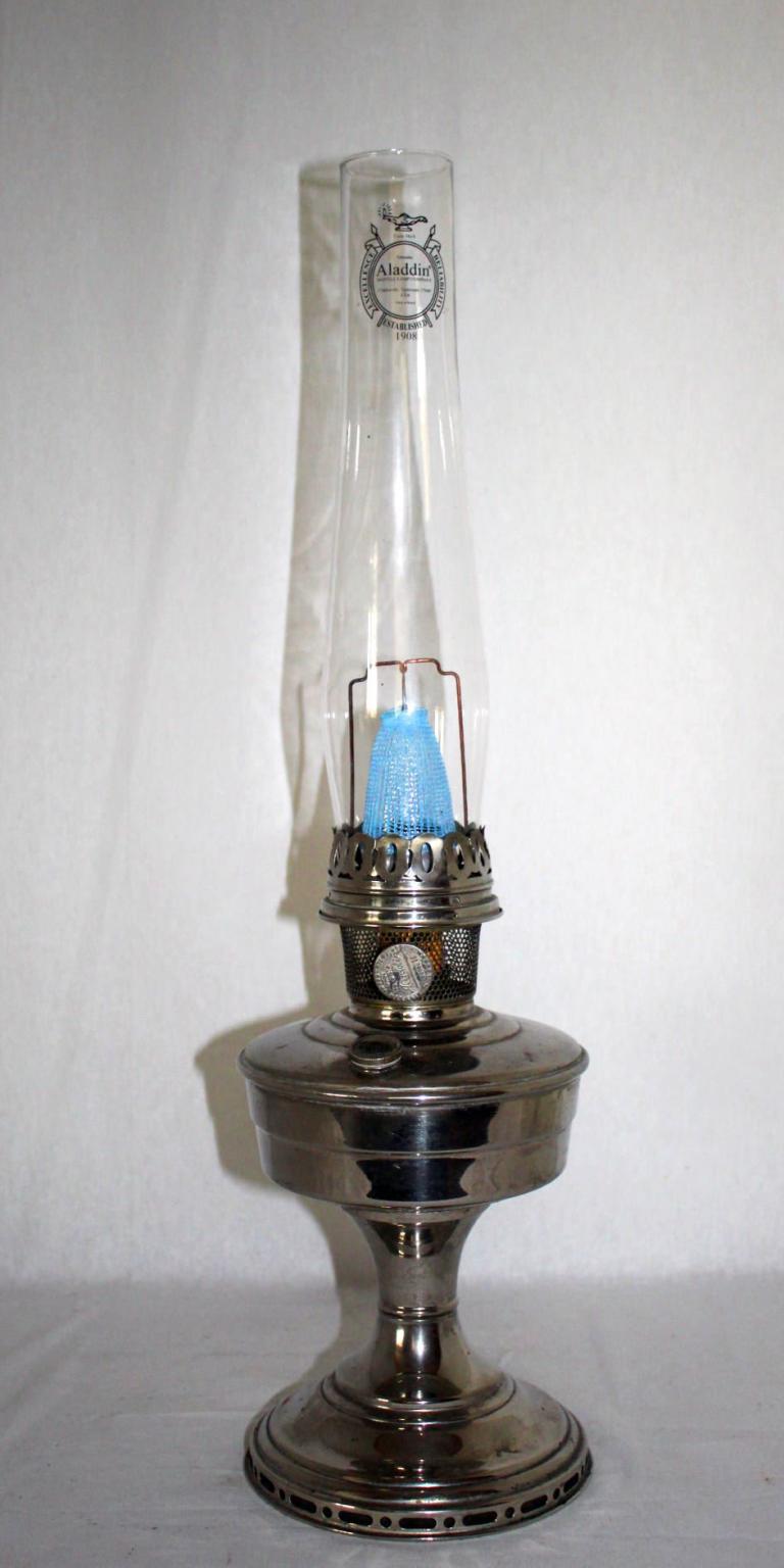 Eine silberfarbene Petroleumlampe mit hohem Glaszylinder und blauem Dochtaufsatz